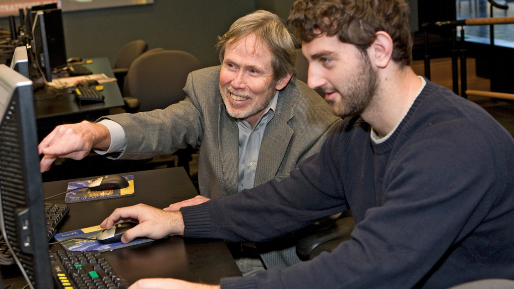 Management Information Systems professor and student work at computer Management Information Systems professor and student work at computer